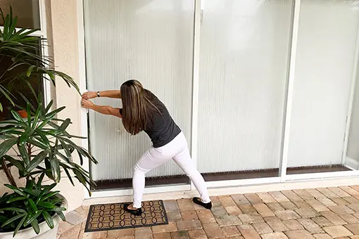 Woman Doing Battle with a Commercial Sliding Glass Door and Screen